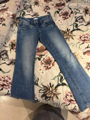 Blå bootcut jeans från Gina Tricot - Snygga blå bootcut jeans från Gina Tricot med klassisk femficksdesign och normalhög midja. Jeansen har en lätt tvättad look och utsvängda ben.Storlek 158 