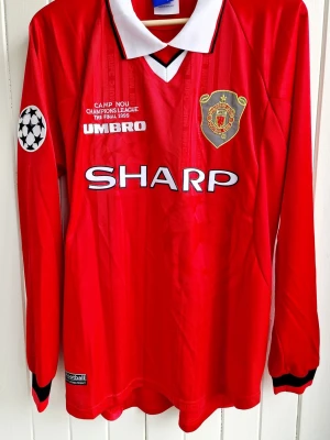 Jesper Blomqvist - Manchester United - CL-final 1999 - Säljer en klassisk fotbollströja, Jesper Blomqvists matchtröja från Champions League-finalen 1999 när hans Manchester United vann över FC Bayern München och blev CL-mästare. Tröjan är en reprint i nyskick och har finalen och datumet inskrivet på bröstet (samma text som Jesper hade på sin tröja under finalen). Långärmad med CL-patch.  XL, men motsvarar mer L/XL i storleken.  #fotboll