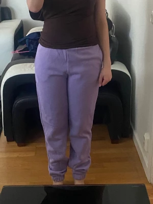 Gina Lila och ljuslila mjukisbyxor - Två par mjukisbyxor i lila och ljuslila färg med resår i midjan och vid bensluten. Byxorna har en klassisk, avslappnad passform och är perfekta för chill dagar. Tillverkade i mjukt och bekvämt material som känns skönt mot huden. Dem blåa kostar 50 då de är använda ett fåtal gånger medans dem lila 70kr då de är helt nya (jag har två par av varje)