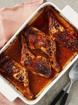 Ugnsrostade kycklingklubbor i form - Fyra ugnsrostade kycklingklubbor i en vit rektangulär ugnsform. Kycklingen är täckt med kryddor och örter och ligger i en smakrik, brunaktig sky. Perfekt till middag eller matlåda.