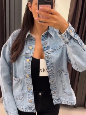 Ljusblå jeansjacka från Zara - Trendig ljusblå jeansjacka från Zara med oversized passform och stora framfickor. Klassisk krage, knappstängning framtill och avslappnad look. Perfekt att slänga över en hoodie eller t-shirt för en cool vibe.