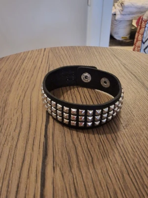 Armband punk svart - Armband punk svart. Ett stilrent minimalistiskt armband i flera rader med fyrkantiga prickar i konstläder. 21,5 cm långt. Bredd 2 cm.