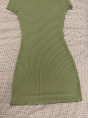 Ljusgrön klänning  - En ribbad ljusgrön klänning i storlek S, vet ej vart ifrån då jag haft den ett tag. Är i bra skick men har en liten mörkgrön prick på sig på insidan av rygg/nack delen (syns ej när den sitter på då det är på insidan). Säljer då den inte används längre🥰