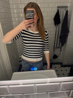 Randig stickad tröja - Snygg stickad tröja med marinblå och vita horisontella ränder. Tröjan har rund halsringning, trekvartsärmar och ribbade muddar vid ärmslut och nederkant. Perfekt för en avslappnad och trendig look.Hör av dig vid frågor ❤️