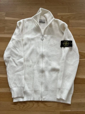 Vit stickad zip-tröja Stone Island - En superunik tröja! Knappt anvand, i nyskick. Tröjan ar tjock, varm och perfekt för våren, både för en fin och bekväm look. Tröjan ar för män. Den är i storlek M. Passar dig som ar ungefar 170-185 cm lång och väger 60-80kg. Hör gärna av dig om du har några frågor eller funderingar!