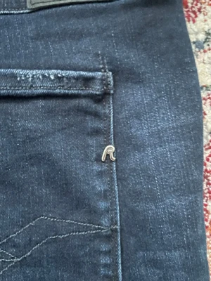 Mörkblå  jeans från Replay - Säljer ett par mörkblå skinny jeans från Replay med snygga slitningar och klassisk femficksmodell. Jeansen har en tight passform och är tillverkade i stretchigt denimtyg för extra komfort. Metalllogga på bakfickan ger en exklusiv touch. Vill bli av med dem så kan sänka priset vid snabb affär 