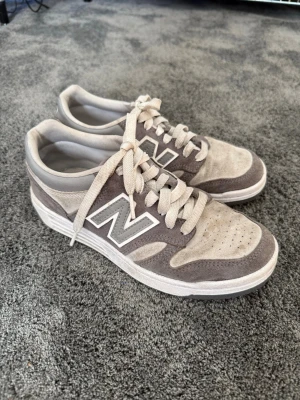 Grå New Balance sneakers - Lette New Balance-sneakers i semsket stoff. Litt bruksslitasje, men fortsatt fine! Kan vaskes av meg gratis med profesjonell sko vasking! Kan leveres eller hentes i Frogner. 
