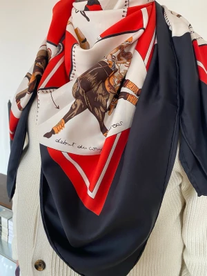 H ermes  silkesscarf med hästmotiv - Snygg silkesscarf från H ermes med klassiskt hästmotiv. Färgerna går i svart, rött, beige och brunt med detaljerade illustrationer och text. Perfekt accessoar för att lyfta din outfit med en lyxig touch och unik design.