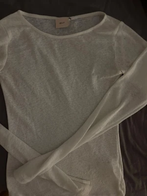 Vit långärmad topp från Nelly - Tunn och lätt vit långärmad topp från Nelly. Modellen är enkel med rund halsringning och har en något transparent känsla. Perfekt att styla lager på lager eller bära som den är för en clean look.