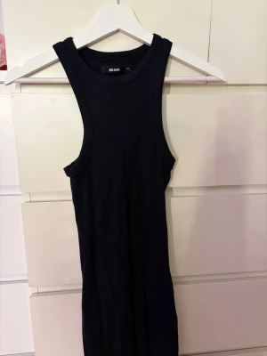 Svart ribbad klänning från Bik Bok - Säljer en svart, ribbad kortklänning från Bik Bok i storlek XS. Klänningen är ärmlös med rund halsringning och har en tight passform som framhäver figuren. Perfekt för dig som gillar en enkel men stilren look.