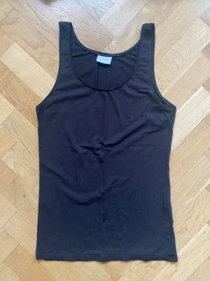 Svart linne från Vila - Ett klassisk svart linne från Vila med rund halsringning och smala axelband. Linnet har en enkel, tight passform som passar perfekt till alla typer av outfits. 