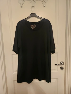 Bomullstopp från Ulla Popken 50/52 - 1 st svart bomullstopp i nyskick från Ulla Popken. Den har rak skärning och halv ärm. Bröstmåttet är 128 cm och längden 71 cm. Storlek 50/52