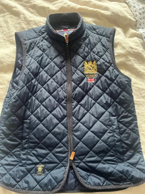 Marinblå Morris dunväst  - Snygg marinblå quiltad dunväst från Morris med guldbroderad logga och brittisk flagga på bröstet. . Perfekt för lager-på-lager och ger en klassisk look .  Mvh Axel :)