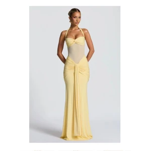 Ljusgul långklänning med halterneck - Supersnygg ljusgul långklänning med halterneck och twistad byst. Klänningen har meshdetalj i midjan, draperad kjol och knyt i nacken. Figurnära passform och elegant fall. Har endast testa på den här klänningen en gång och säljer den då den va lite stor och för lång på mig och då jag inte heller han lämna tillbaks den.