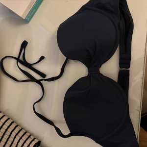 Mörkblå bikiniöverdel med knyt - Snygg mörkblå bikiniöverdel med vadderade kupor och knyt i nacken. Klassisk modell med enkel design och justerbart band i nacken. De är storlek L men skulle verkligen säga en M!!