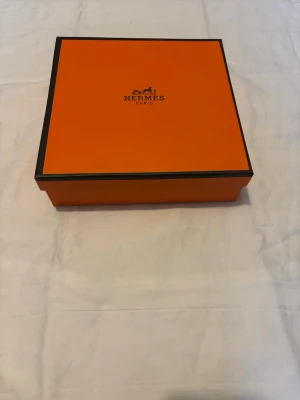 H belte med dustbag och låda - Säljer ett exklusivt belte från H, levereras i klassisk orange H-box och med tillhörande dustbag med logga. Perfekt för dig som gillar lyxiga accessoarer och vill ha något riktigt ikoniskt i din samling.