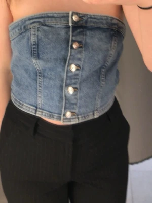Blå denim tubtopp med knappar - Trendig blå jeanstopp  med knappar framtill. Från h&m i storlek s, aldrig använd. Säljer den för den är för stor.