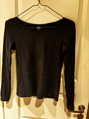 Svart långärmad topp i bomull - En enkel och stilren svart långärmad topp med rund halsringning. Tillverkad i mjuk bomull som känns skön mot huden. Perfekt basplagg att matcha med olika outfits.