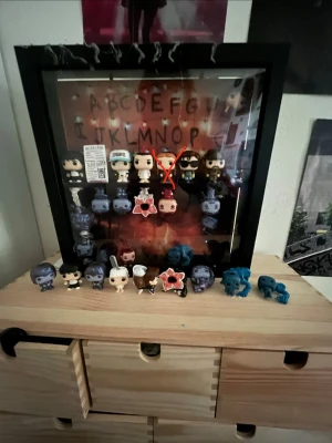 Stranger Things Funko Pop samling - Säljer en Stranger Things-inspirerad Funko Pop samling med flera minifigurer i olika färger och former. Figurerna står i och utanför en svart glaslåda med bakgrund av alfabetet och lampor, inspirerat av serien. Perfekt för fans av Stranger Things och popkultur. 12kr/st och alla för 500kr. Steve har åkt ner i tavlan men han finns också. Will kostar 70 kr och vanliga Max är INTE till salu!!