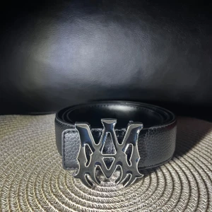 Svart skärp med stor silverdetalj - Snyggt svart skärp med en stor, unik silverspänne i metall. Skärpet har en stilren och modern look, perfekt för att lyfta vilken outfit som helst. Tillverkat i skinn för en exklusiv känsla.