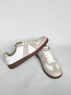 Vita och beige sneakers med mockadetaljer - Stilrena sneakers i vitt och beige med ovandel i slätt läder och mockadetaljer. Skorna har bruna gummisulor och vita skosnören. Perfekta för en clean och modern look. Klassisk låg modell som passar till det mesta.