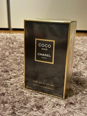 Chanel Coco Noir Eau de Parfum 100ml - Lyxig parfym från Chanel, Coco Noir Eau de Parfum i elegant svart och guld förpackning. Flaskan rymmer 100 ml och har en exklusiv, modern design. Perfekt för dig som gillar sofistikerade och djupa dofter med en touch av mystik.