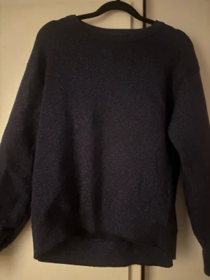 Mörkblå glittrig stickad tröja - Säljer en mörkblå stickad tröja med diskret glitter som ger ett snyggt skimmer. Materialet känns mjukt och stretchigt. Tröjan har används en gång!🫰