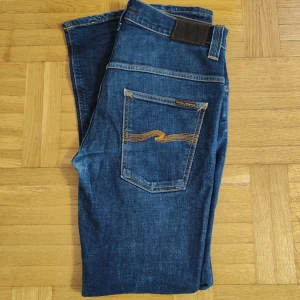 Nudie Jeans - Nudie Jeans för män i storlek Waist 32 / Lenght 32. Jeans är Mörkblå med orange stitching som gör det otroligt elegant. Nyskick inga skador/brister. Modellen är Tape Ted. Hör av er vid intresse eller frågor. PRIS KAN DISKUTERAS!