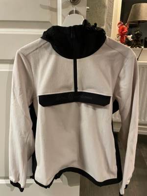 Sail Racing fleece/jacka - Säljer en snygg vit fleece/jacka från Sail Racing med svarta detaljer och halv dragkedja framtill. svart logga på bröstet. Tillverkad i mjukt material oanvänd men prislappen är borta då tanken var att använda men var för tajt.