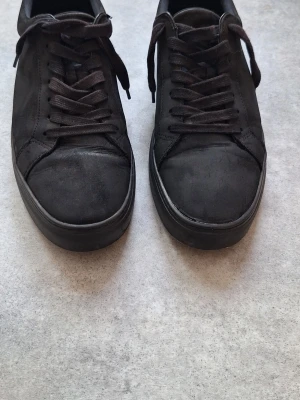 Svarta sneakers från Vagabond - Stilrena helsvarta sneakers från Vagabond med lågt skaft och klassisk snörning. Ovandelen är i mocka och sulan är svart. Perfekta för dig som gillar minimalistisk och clean stil. Mäter 27 cm invändigt. Stl 42