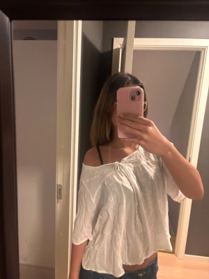 Vit blus med brodering - Jättegullig vit blus, sälj pågrund av ingen användning❤️  är i storlek S men väldigt lös och flowy OBS! Ena pompom på trådarna man knyter är av!
