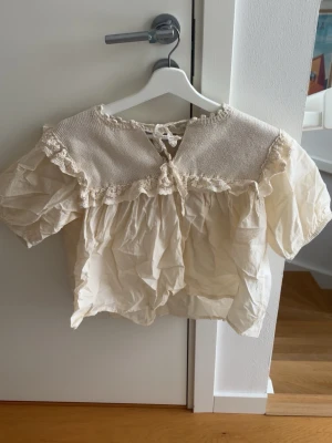 Krämvit blus med volang från Zara - Supersöt krämvit blus från Zara med korta puffärmar och volangdetaljer. Jätte skön blus att ha under sommaren. Använd 1 gång!! 