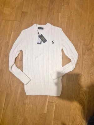 stickad vit Ralph Lauren tröja - En stickad vit Ralph Lauren tröja som var för liten för mig. Inget fel med tröjan utan super fin med prislapp på och storlek xs-s Skulle nog säga mer åt xs hållet🤗   (Går att sänka priset vid snabb förhandling)