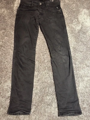 Svarta replay jeans  - Säljer ett par svarta jeans med rak passform och klassisk femficksdesign. Jeansen har normal midja och är tillverkade i ett mjukt denimtyg. Perfekta för dig som gillar en enkel och stilren look.