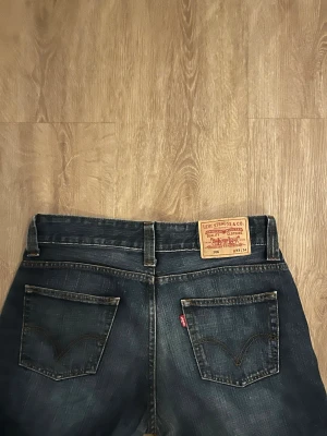 Levi's mörkblå raka jeans 506 - Säljer ett par klassiska mörkblå jeans från Levi's med raka ben. Jeansen har två bakfickor med den ikoniska Levi's-sömmen och ett läderpatch bak i midjan. Tillverkade i slitstark denim och har en tidlös look.