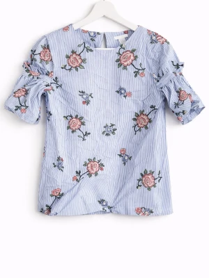 Blommig blus med volangärm från H&M - Söt blus från H&M i ljusblått med vita ränder och broderade blommor i rosa och grönt. Blusen har volangdetaljer på de korta ärmarna och en rak passform. Perfekt för dig som gillar romantiska och trendiga plagg.