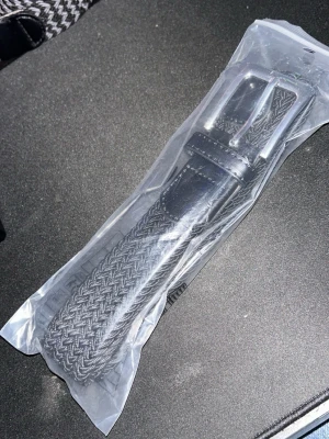 Svart flätat bälte med skinn-detaljer - Snyggt svart flätat bälte med detaljer i skinn och metallspänne. Passar perfekt till jeans eller chinos. Enkel att justera och ger en clean vibe till outfiten.