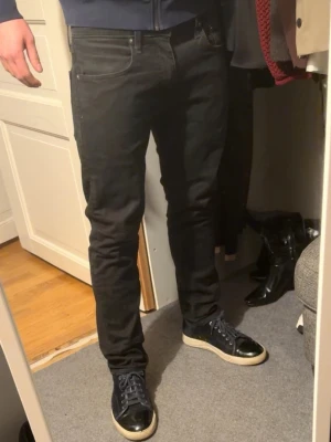 Svarta Levi's jeans herr - Säljer ett par svarta jeans från Levi's med klassisk femficksmodell och rak passform. Jeansen har en diskret röd Levi's-tag på bakfickan och är tillverkade i ett slitstarkt bomullsmaterial. Perfekta till sneakers och hoodie.