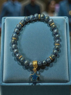 Blått pärlarmband med stjärnhänge - Snyggt armband med glittrande blå pärlor och guldfärgade detaljer. Armbandet har ett blått stjärnhänge i metall som ger en cool touch. Perfekt accessoar för att lyfta din stil.