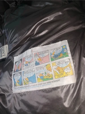 Svart puffer dunjacka från Moncler - Snygg svart dunjacka från Moncler med glansig finish och klassisk pufferdesign. Jackan har huva, dragkedja framtill, två sidofickor med dragkedja och en ärmficka med Moncler-logga. Perfekt för kalla dagar och riktigt trendig look. NFC finns på armen. Monclear påsen ingår också. Vid frågor eller fler bilder skriv gärna, priset går att diskutera