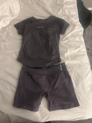Träningsset  - Säljer ett träningsett med en kortärmad t-shirt och matchande shorts. Setet är gjort i ett stretchigt och snabbtorkande material som passar perfekt för gymmet eller löpning. Diskret logga på både tröja och shorts.