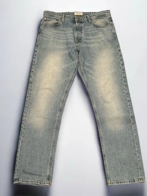 Ljusblå raka jeans från Jack & Jones  - Ljusblå jeans från Jack & Jones. Rak passform och klassisk femficksmodell. Tillverkade i bomull med metallknappar och nitar. Jeansen är i mycket bra skick, inga defekter!                                                   Storlek: W33, L34.                                                                Modell: Loose/Chris