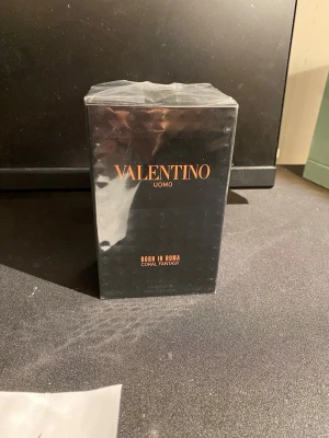Valentino Uomo Born In Roma Coral Fantasy - Valentino Uomo Born In Roma Coral Fantasy är en exklusiv herrparfym i en elegant svart kartong med orange text. Förpackningen har en lyxig, geometrisk struktur på sidorna och är inslagen i plast. Märket Valentino står tydligt på framsidan. Helt ny med kvitto och sephora tag