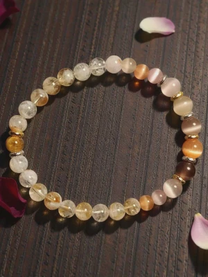 Armband med pärlor i jordnära toner - Snyggt armband med runda pärlor i olika jordnära färger som beige, brunt, guld och rosa. Pärlorna är genomskinliga och halvgenomskinliga, vissa med glittrande inslag. Armbandet har små guldfärgade detaljer mellan vissa pärlor. Pärlorna är kristall stenar av citrin och kattöga.  Perfekt accessoar för en trendig look. Armbandet är elastiskt.