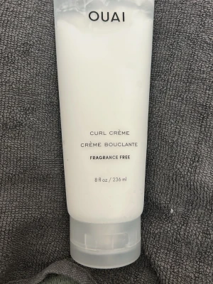 OUAI Curl Crème Fragrance Free 236ml - OUAI Curl Crème är en doftfri stylingkräm för lockigt hår. Kommer i en vit, mjuk plasttub med genomskinligt lock och rymmer 236 ml. Perfekt för att framhäva och definiera lockar utan parfym. Använt lite men passade inte mitt hår