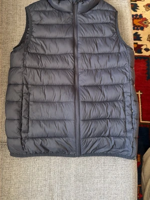 Mörkblå dunväst från MNG - Snygg mörkblå dunväst från MNG med quiltad design och dragkedja framtill. Västen har två sidofickor och en hög krage som ger extra värme. Perfekt för lager på lager och enkel att matcha med olika outfits.