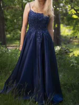 JJ’s House balklänning mörkblå - En jätte fin balklänning från JJ’s House i storlek 38/40 ungefär. Den är omsydd från en storlek 42. Midjemått rakt över: 39/40 cm. Midjemått runt om innefrån: 78/79 cm. Byst: 90 cm ungefär men de är inräknat med kuporna som sticker ut lite. Längd: 130 cm. Den har inbyggda inlägg till brösten. Den har justerbara band men ett band fastnar inte dit man justerar det men de går super lätt att sy fast som jag gjorde men tog bort nu(bild 6 den åt höger). Nypris:1900 kr. Har en liten fläck på kjolen.