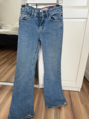 Blå bootcut jeans från Superdry - Säljer ett par klassiska blå bootcut jeans från Superdry Denim. Jeansen har fem fickor, normal midja och är tillverkade i slitstark bomullsdenim. Perfekta för en avslappnad och trendig look. Passar dig som gillar tidlös stil och sköna jeans. Nypriset var 1200kr