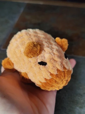 Mysig capybara mjukisdjur - Söt liten capybara i mjuk plysch med beige och bruna toner. Den har små öron, svans och tassar samt broderade svarta ögon. Perfekt som dekoration eller att ha i väskan. Tillverkad i fluffigt tyg som känns gosigt att hålla i.