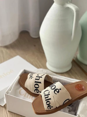 Beige sandaler från Chloé - Nytt pris 4100sek Snygga sandaler från Chloé med breda, korslagda band i beige canvas och svart logotyptryck. Sulan är i brunt läder med kontrastsömmar och öppen tå. Perfekta för en trendig och avslappnad look.